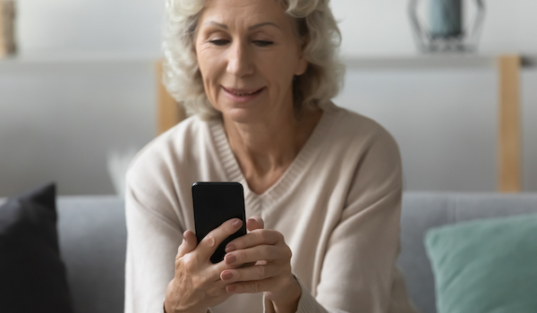Happy older woman using smartphone for video call from home